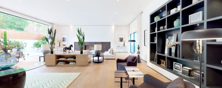 Interno di un soggiorno moderno e luminoso con arredi di design, grandi finestre, piante verdi e dettagli eleganti, ideale per servizi fotografici di interni e web.