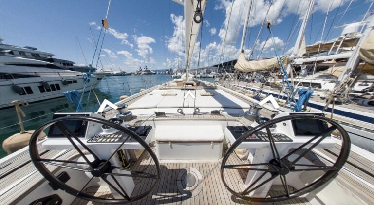 Tastiera e controller di un yacht di lusso nel porto, vista frontale delle cabine di comando con yacht moderni all'ancora in un marina soleggiato.